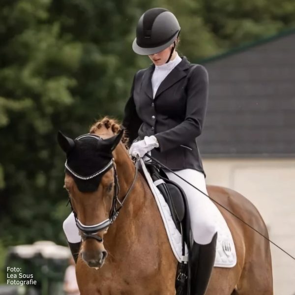 Reiterin des Reitstall Teuterhof bei einer Turnierprüfung. Sie sitzt auf einem Pferd und trägt Turnierreitsachen.
